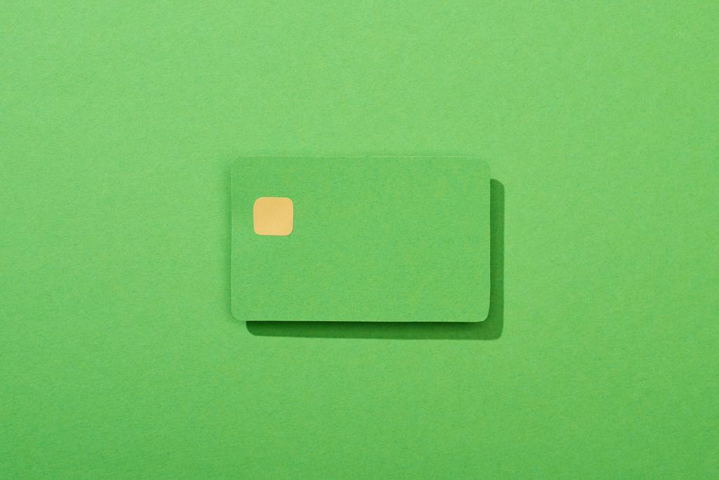 Yeşil arkaplanda renkli boş kredi kartının üst görünümü - Fotoğraf, Görsel