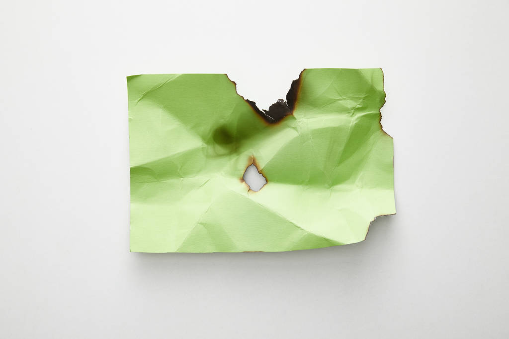 top view of empty crumpled and burnt green paper on white background - Photo, Image
