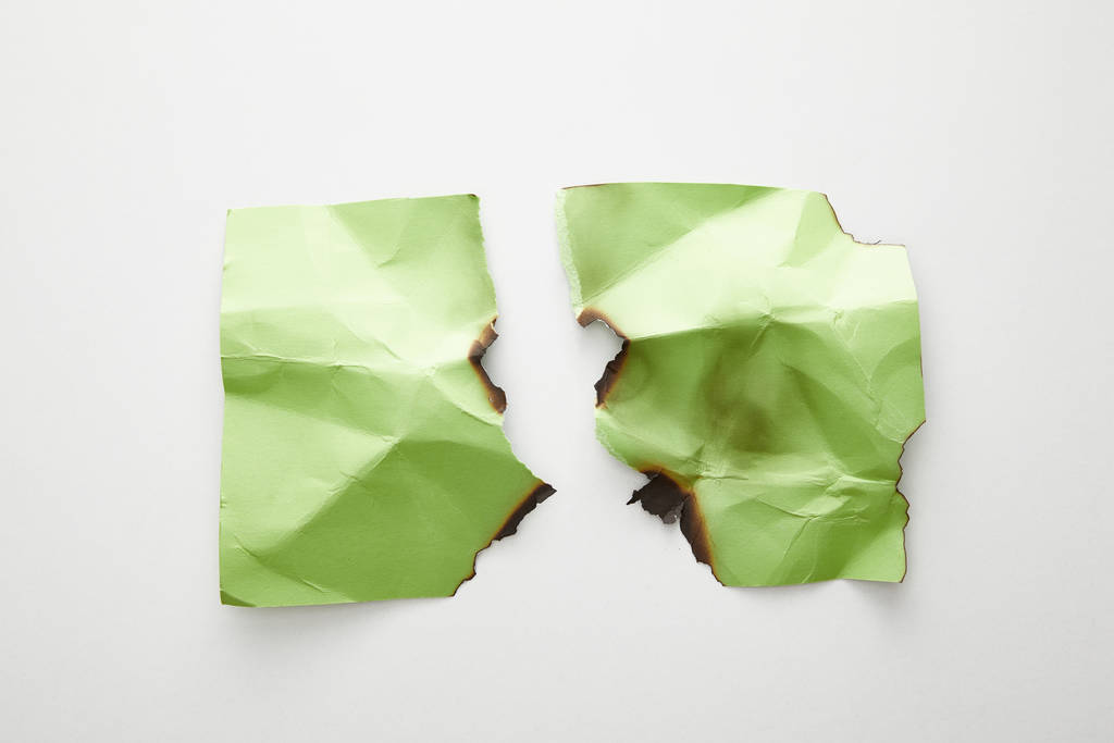 top view of empty crumpled, torn and burnt green paper on white background - Photo, Image