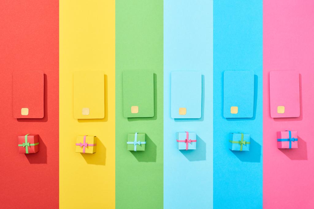 vista superior de tarjetas de crédito vacías multicolores y cajas de regalo sobre fondo de arco iris
 - Foto, Imagen