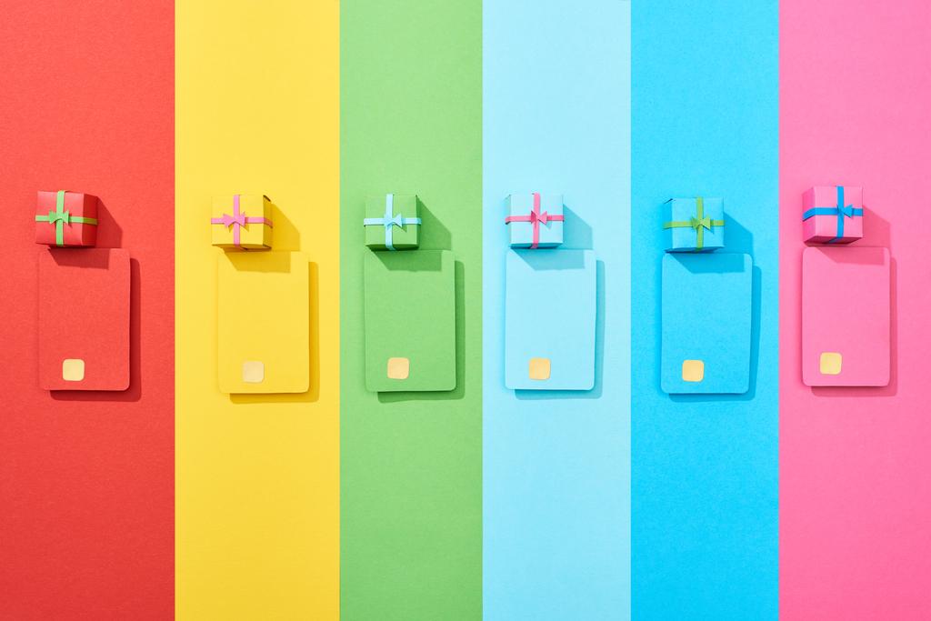 vista superior de tarjetas de crédito vacías multicolores y cajas de regalo sobre fondo de arco iris
 - Foto, Imagen