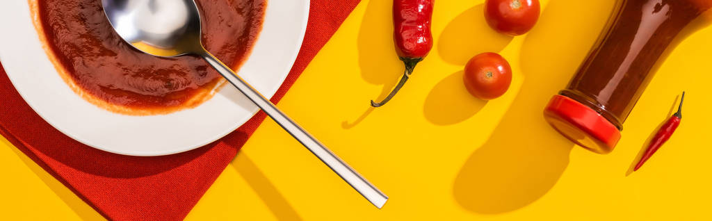 Κάτοψη του πιάτου και του μπουκαλιού με κέτσαπ, πιπεριές τσίλι και ντοματίνια σε κίτρινο φόντο, πανοραμική λήψη - Φωτογραφία, εικόνα