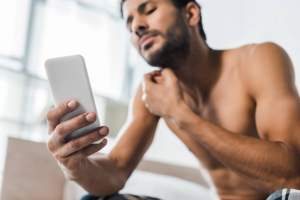 selective focus of handsome and sexy bi-racial man using smartphone in morning  - Photo, Image