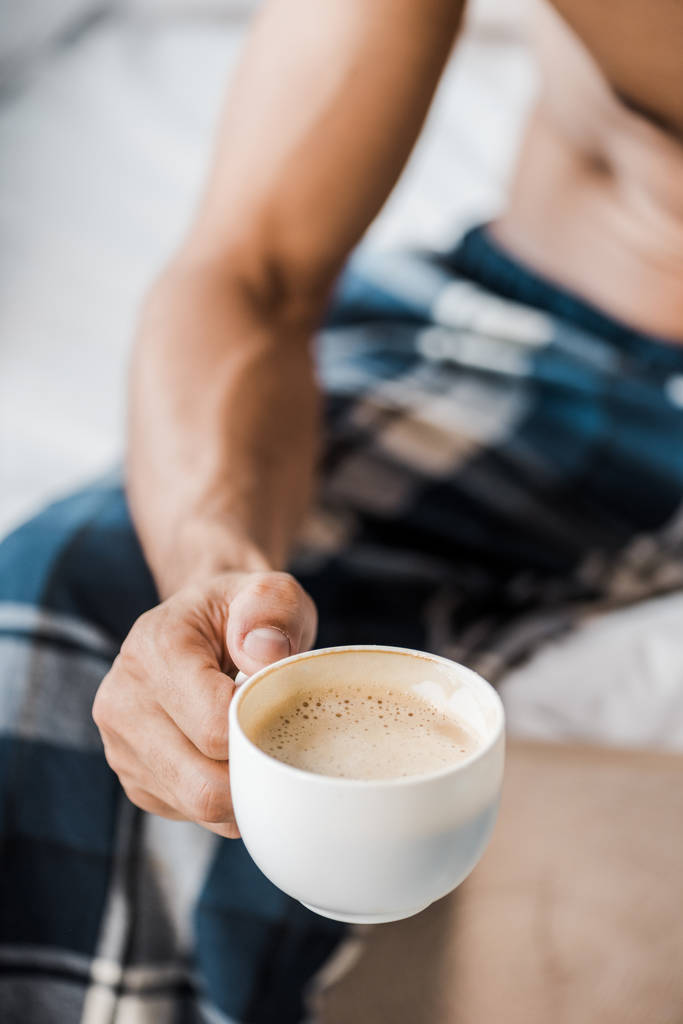 Обрезанный вид бирасового мужчины, держащего чашку кофе по утрам
  - Фото, изображение