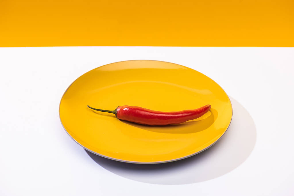 Mausteinen chili-pippuri valkoisella pinnalla keltaisella pohjalla
 - Valokuva, kuva