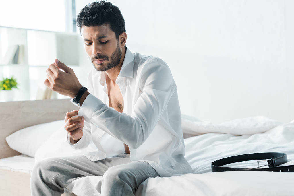 jóképű bi-rasszista férfi öltözködik és ül az ágyon reggel  - Fotó, kép