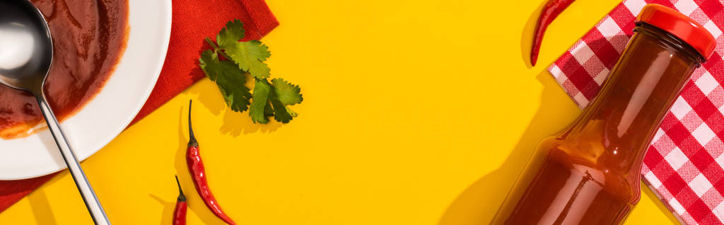 Вид сверху домашнего кетчупа с перцем чили и кинзой на желтом фоне, панорамный снимок
 - Фото, изображение