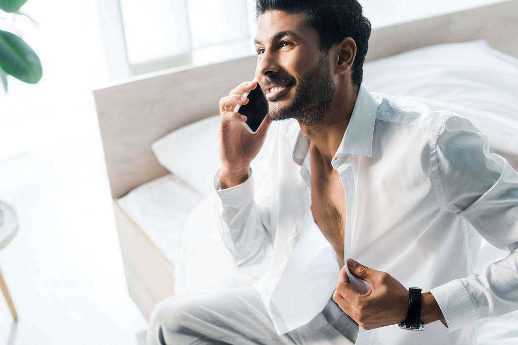 vue grand angle de sourire et bel homme bi-racial parlant sur smartphone le matin
  - Photo, image