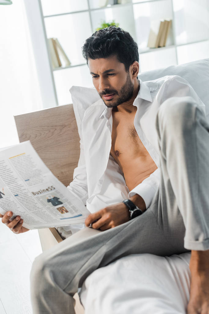 przystojny bi-rasowy człowiek czyta gazetę na łóżko rano  - Zdjęcie, obraz