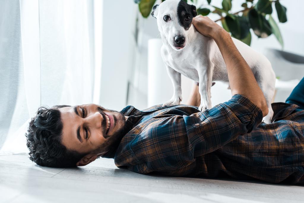 guapo bi-racial hombre sonriendo y sosteniendo jack russell terrier
 - Foto, imagen