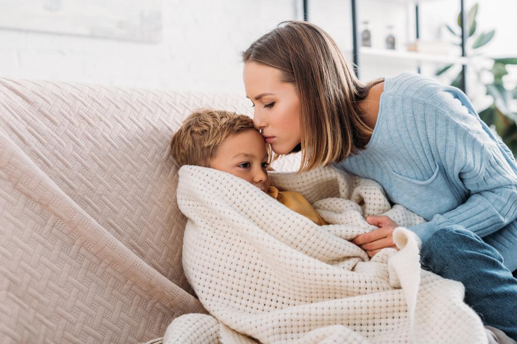 cuidar mãe beijando doente filho envolto em cobertor
 - Foto, Imagem