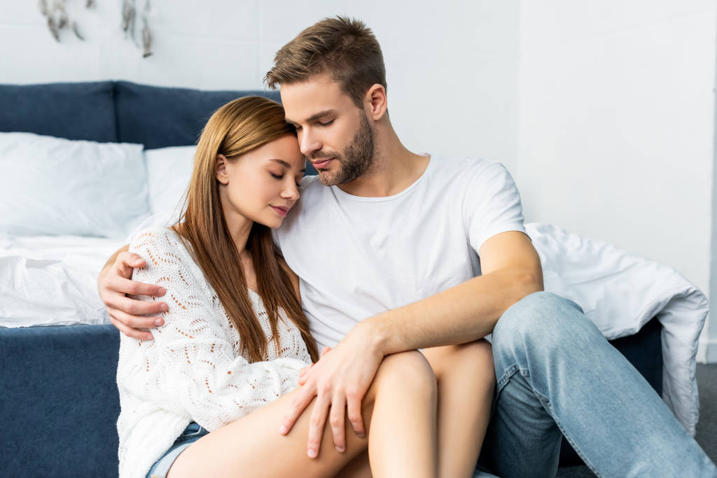 handsome man hugging attractive woman with closed eyes in apartment  - Photo, Image