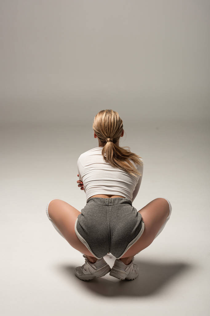πίσω όψη του νεαρού σέξι κορίτσι σε σορτς twerking σε λευκό φόντο - Φωτογραφία, εικόνα