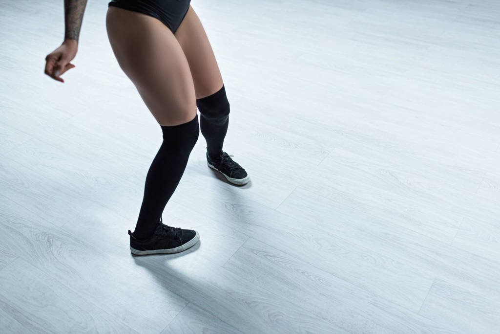 Ausgeschnittene Ansicht tätowierter Mädchen im schwarzen Outfit, die im Studio tanzen - Foto, Bild