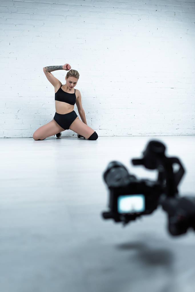 foco seletivo de câmera digital de tiro sexy menina loira em roupa preta perto da parede de tijolo branco
 - Foto, Imagem