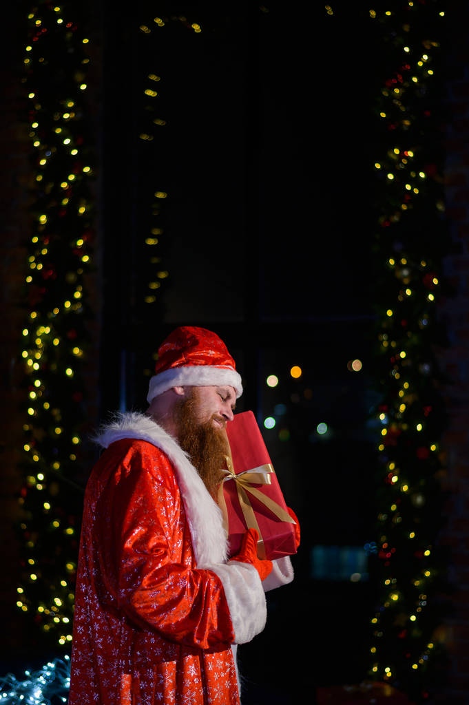 Κακός Άγιος Βασίλης στο φόντο της Χριστουγεννιάτικης διακόσμησης. Ένας άντρας με κοστούμι του Αϊ Βασίλη μετά την πρωτοχρονιά.. - Φωτογραφία, εικόνα