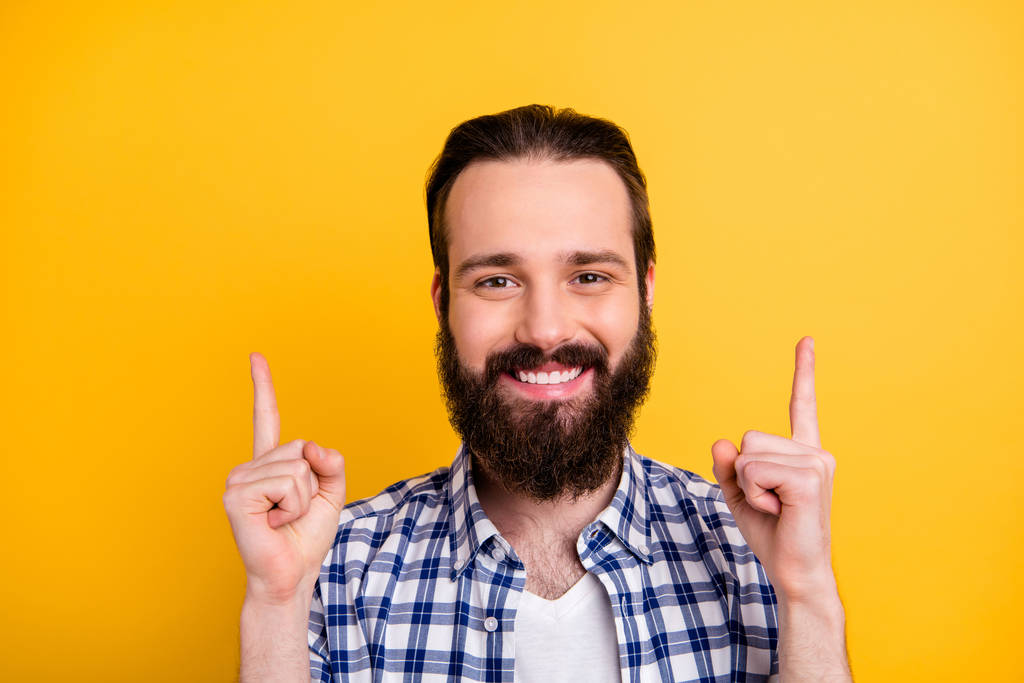 Detailní-up portrét jeho pěkný atraktivní veselý veselý sebevědomý vousatý chlap v kostkované košili ukazující dva ukazováčky nahoru reklama izolované na jasném živém lesku pulzující žlutá barva pozadí - Fotografie, Obrázek