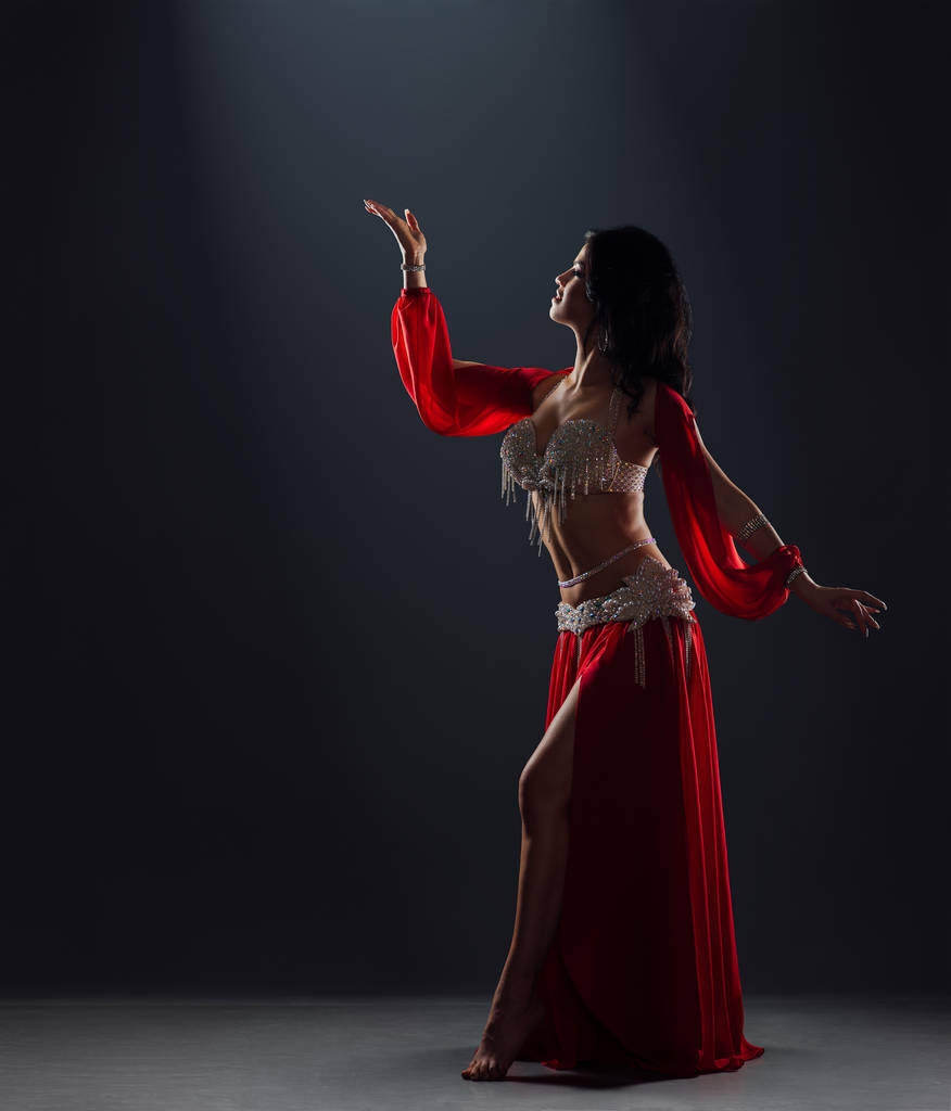 beautiful black-haired girl in red ethnic dress dancing oriental - Photo, Image