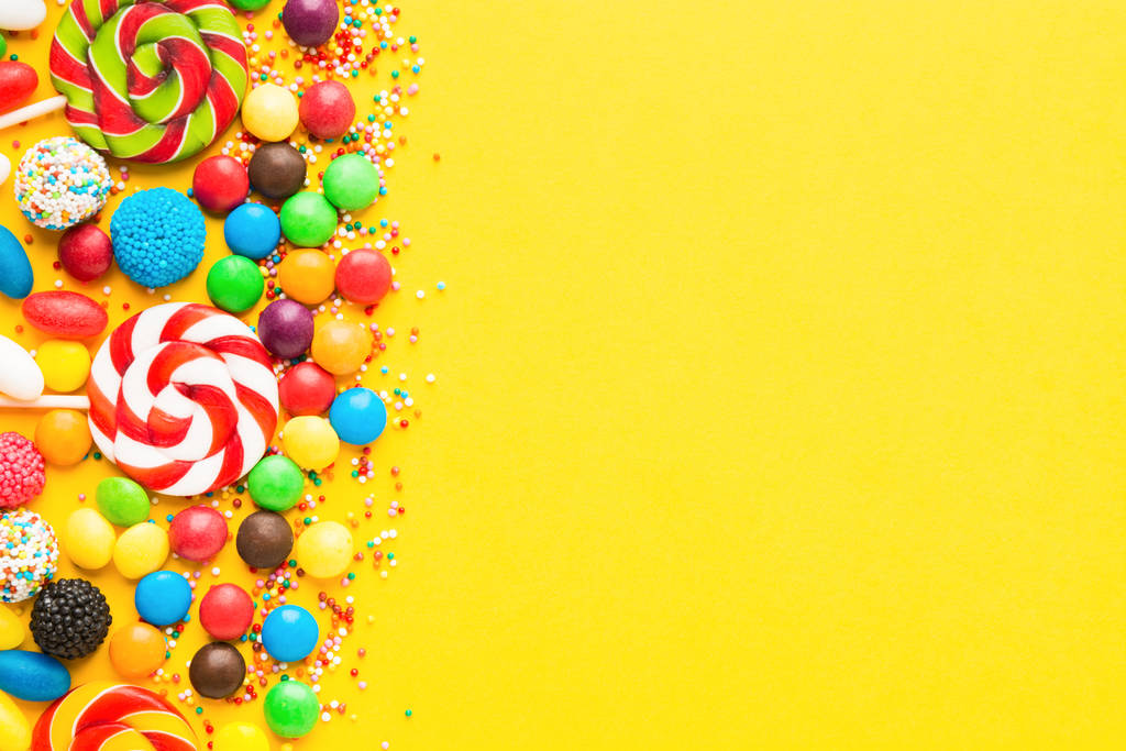 Colorful candies over yellow background. Top view. Flat lay - Photo, Image