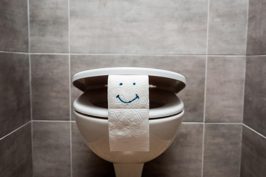 Modern tuvaletlerde seramik temiz klozet ve gülen yüzlü tuvalet kağıdı.  - Fotoğraf, Görsel