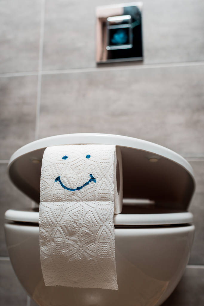Modern tuvaletlerde seramik temiz klozet ve tuvalet kağıdına gülümseyen yüzle yakın görüş.  - Fotoğraf, Görsel