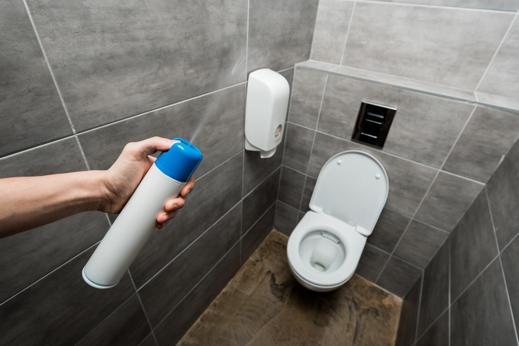 vista cortada do homem pulverizando ambientador no banheiro moderno com azulejo cinza
 - Foto, Imagem