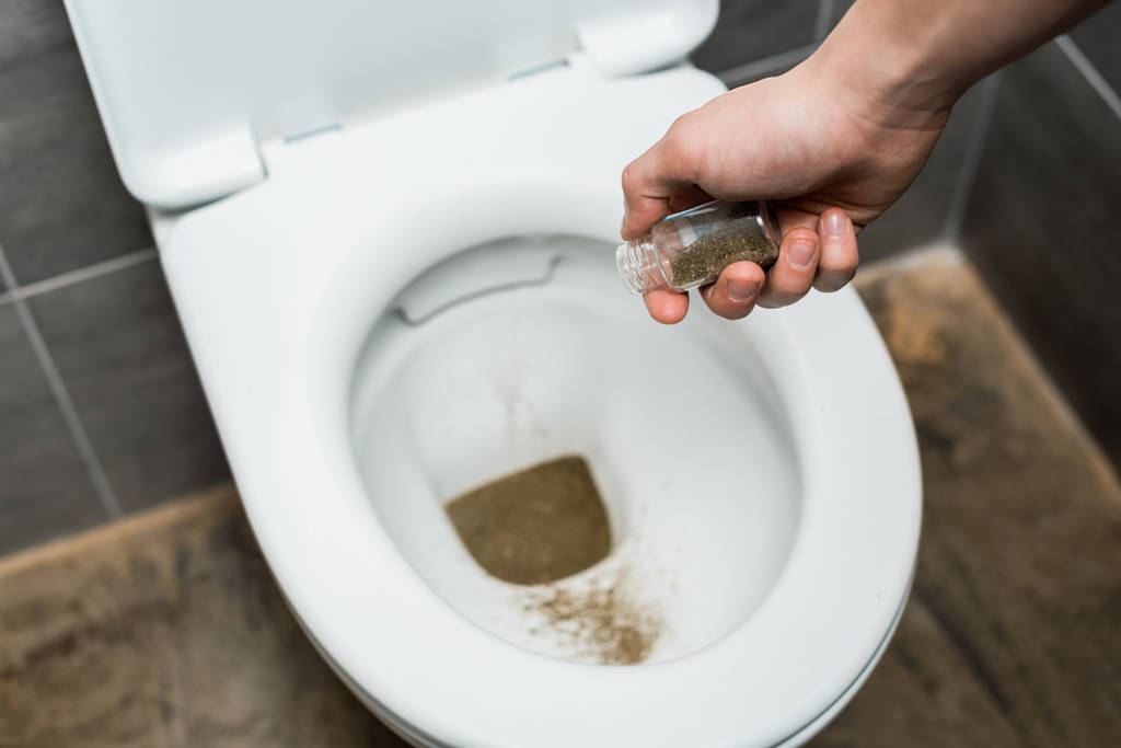 vue recadrée de l'homme jetant de la marijuana dans un bol de toilette
 - Photo, image