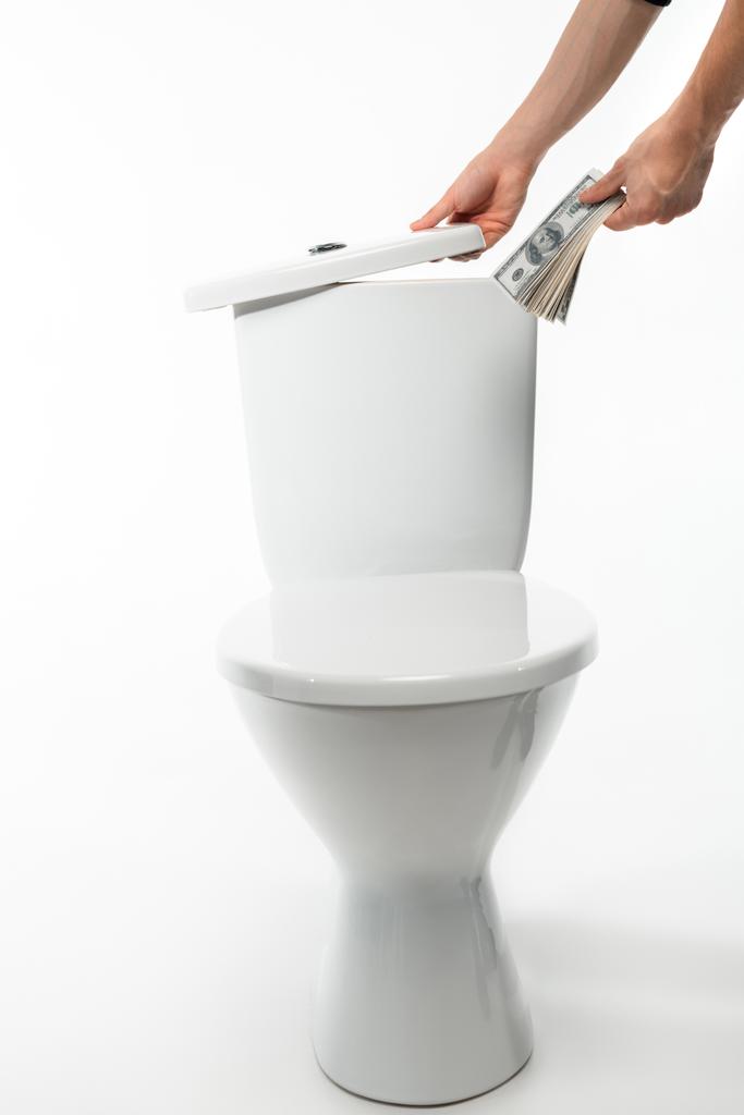 καλλιεργημένη άποψη της γυναίκας κρύβεται δολάρια σε κεραμικά καθαρό λεκάνη τουαλέτας σε λευκό - Φωτογραφία, εικόνα