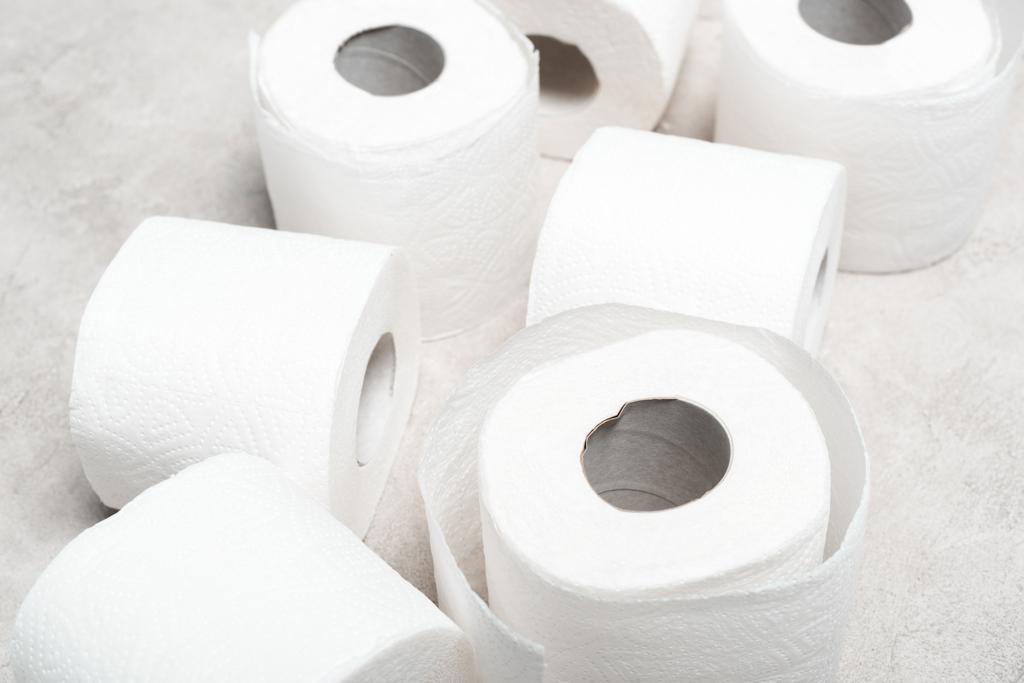 Nahaufnahme von Toilettenpapierrollen auf grau strukturierter Oberfläche - Foto, Bild