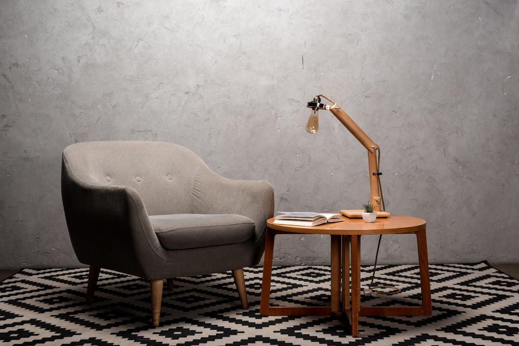 sisätilojen olohuone mukava harmaa moderni nojatuoli lähellä puinen pöytä ja lamppu matolla
 - Valokuva, kuva