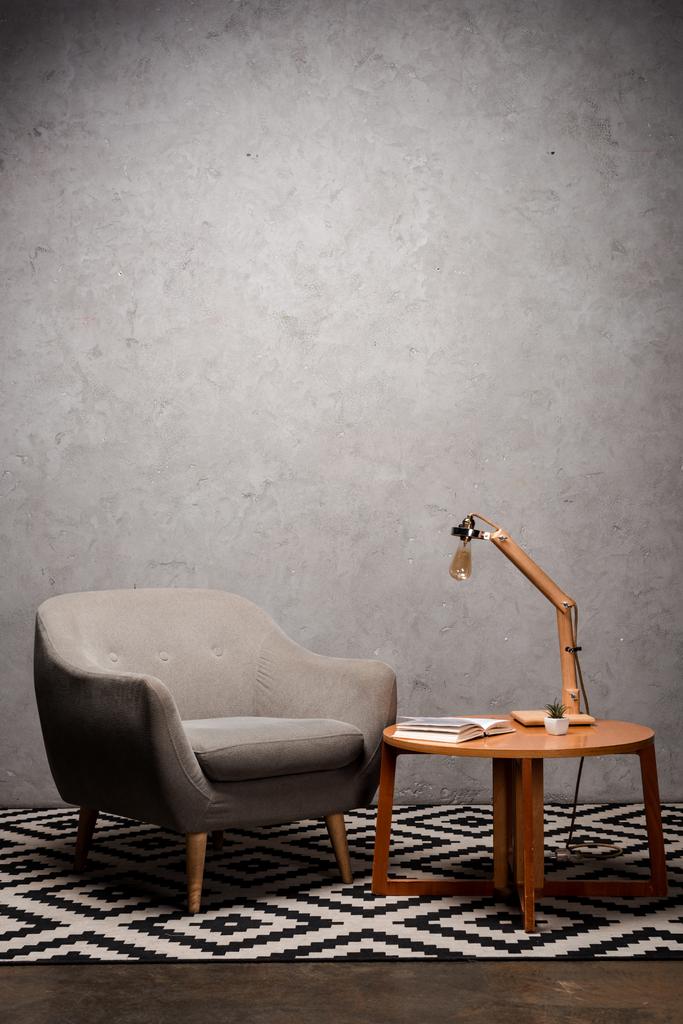 interiér obývacího pokoje s pohodlným šedým moderním křeslem u dřevěného stolu a lampou na koberci - Fotografie, Obrázek