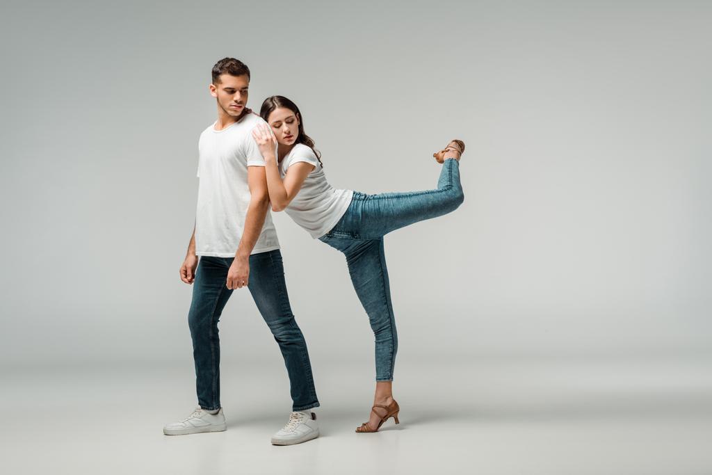 Bailarinas en camisetas y jeans bailando bachata sobre fondo gris
  - Foto, Imagen