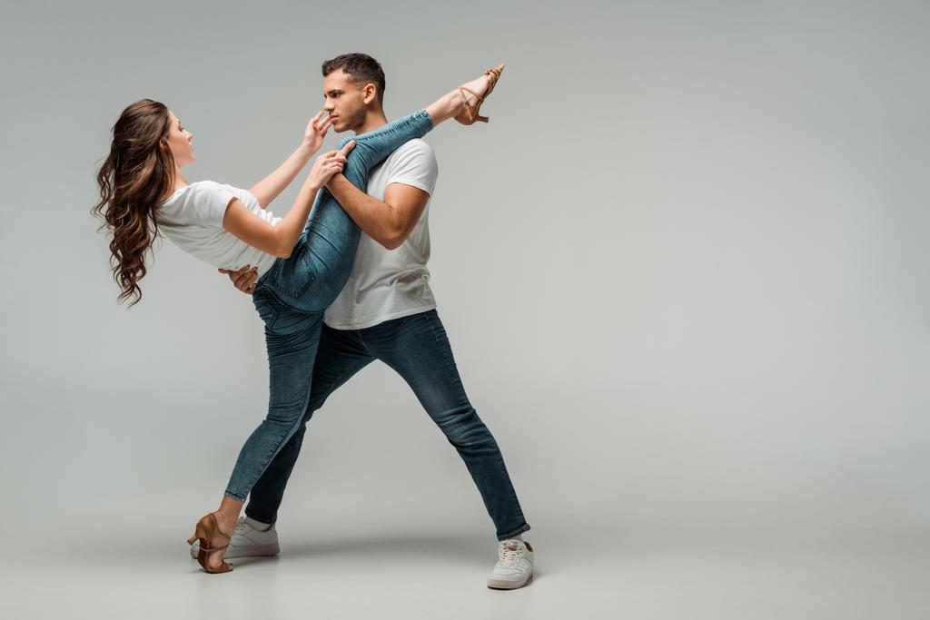 dancers in t-shirts and jeans dancing bachata on grey background  - Photo, Image