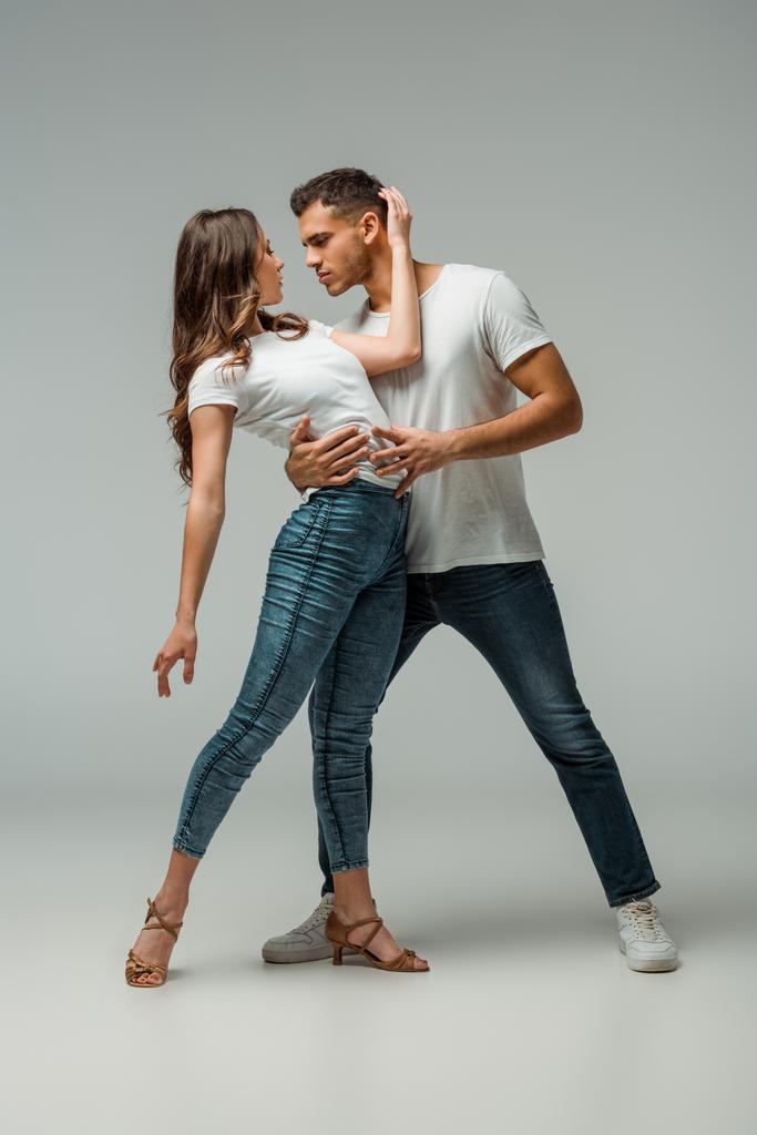 танцоры в футболках и джинсах, танцующие бачату на сером фоне
  - Фото, изображение