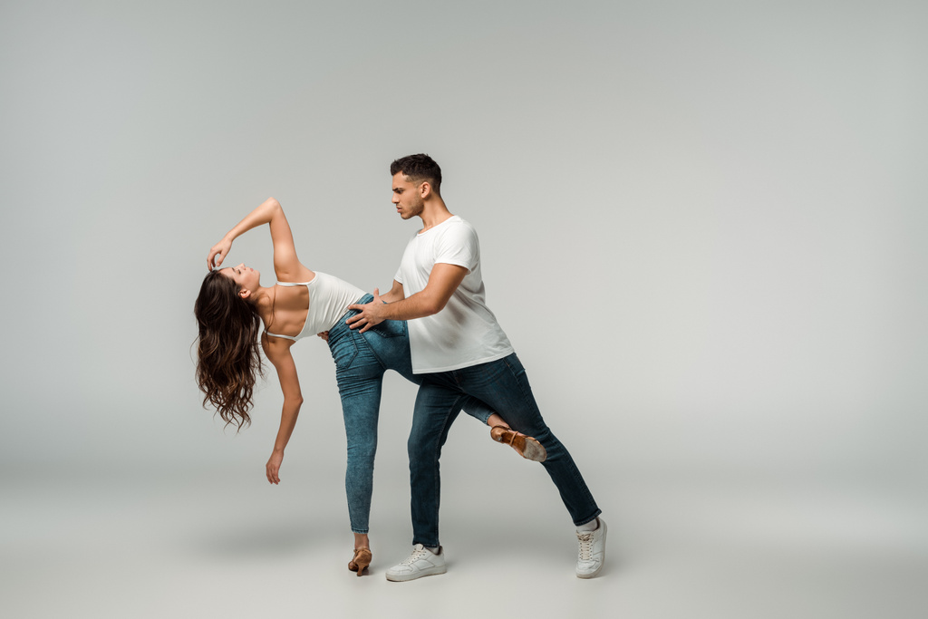 танцюристи в джинсах танцюють баната на сірому фоні
  - Фото, зображення