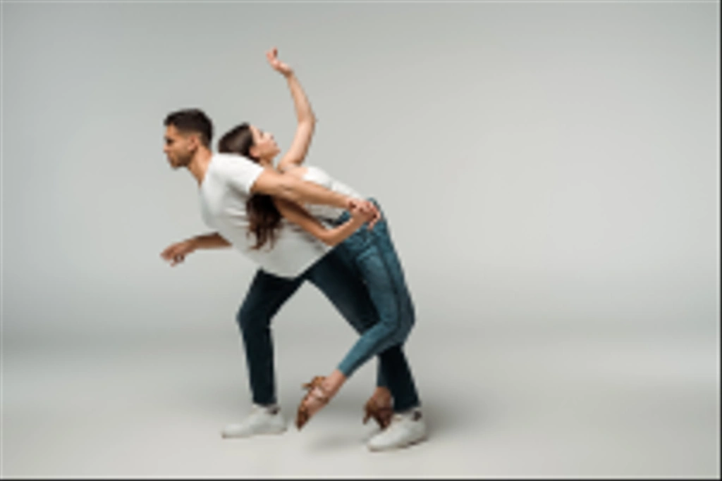 Seitenansicht von Tänzern in Jeans, die Bachata auf grauem Hintergrund tanzen  - Foto, Bild