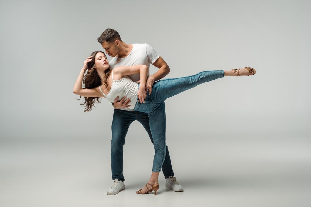 ballerini in jeans jeans danza bachata su sfondo grigio
  - Foto, immagini
