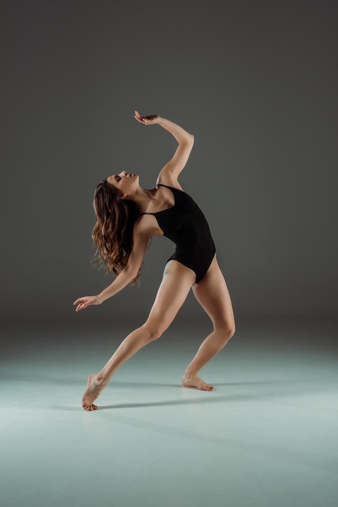 atraktivní tanečnice v černošky bodysuit tanec moderní na tmavém pozadí  - Fotografie, Obrázek