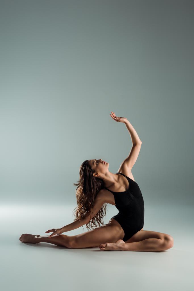 atractiva bailarina de body negro bailando contemporáneo sobre fondo gris
  - Foto, Imagen