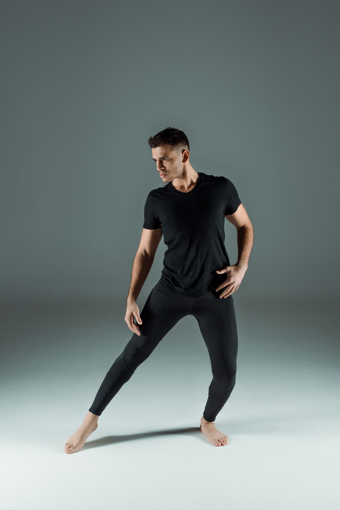przystojny tancerz w czarny legginsy i t-shirt taniec współczesny na ciemnym tle - Zdjęcie, obraz