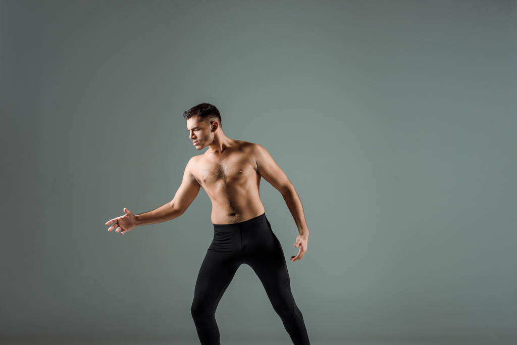 ブラック・レギンスのハンサムなダンサーが現代的にグレーで孤立して踊る  - 写真・画像