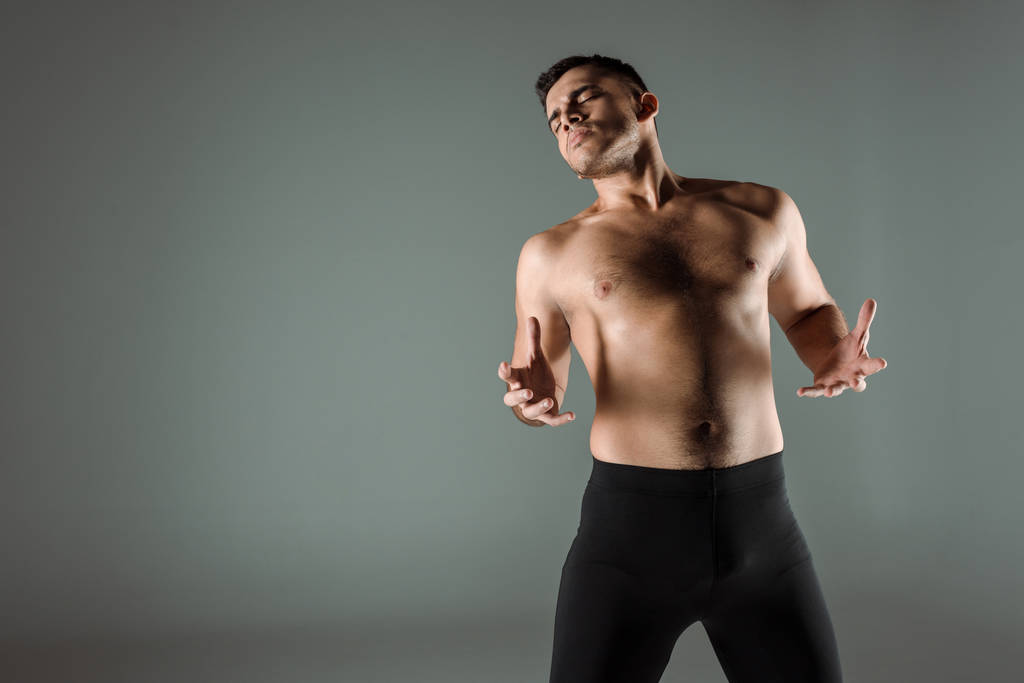 guapo bailarín con los ojos cerrados en negro leggings bailando contemporáneo aislado en gris
 - Foto, Imagen