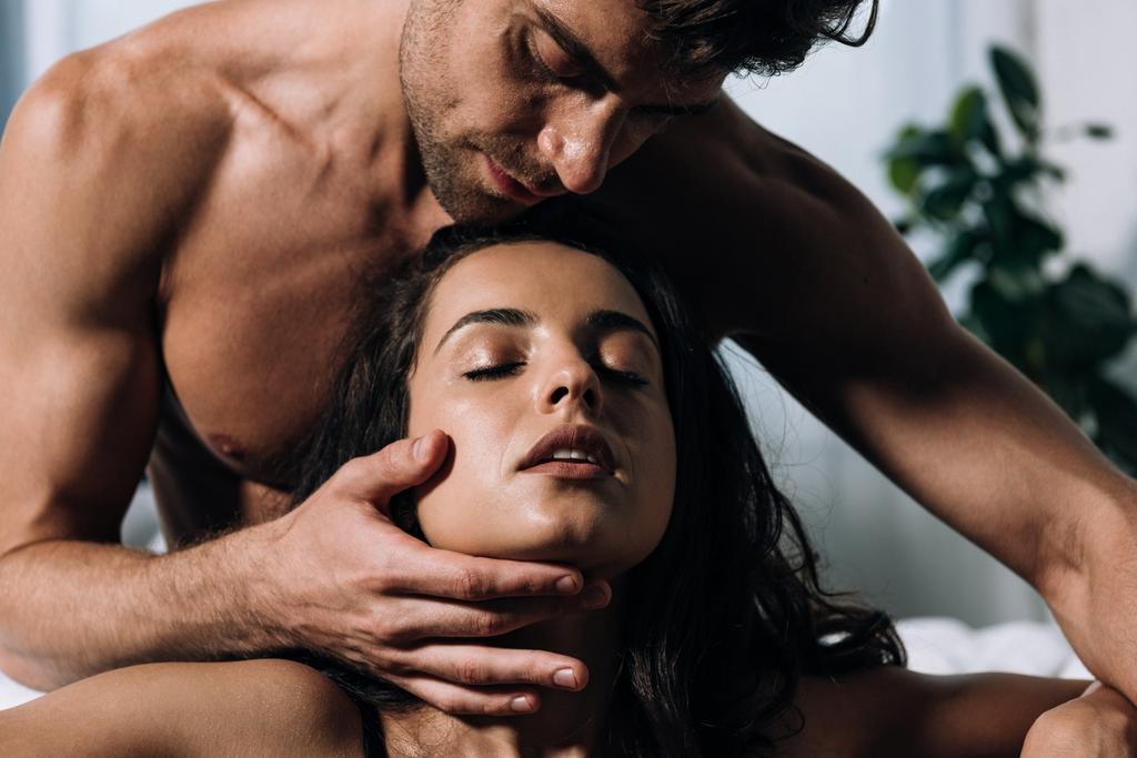 sexy, shirtloze man aanraken gezicht van verleidelijke vriendin  - Foto, afbeelding