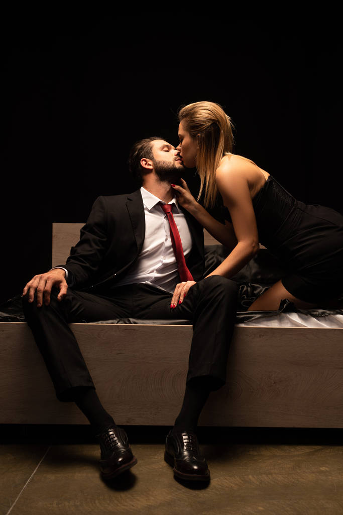 красивая элегантная соблазнительная пара целуется и сидит на кровати в темной комнате
 - Фото, изображение