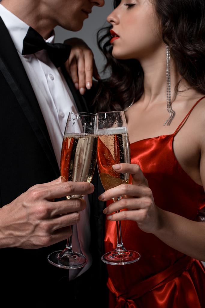 sensual couple clinking with champagne glasses, isolated on grey - 写真・画像