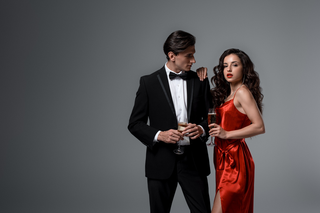 krásný slavnostní pár drží sklenice šampaňského, izolované na šedé - Fotografie, Obrázek