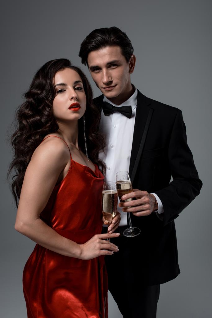 Romantisch feestelijk paar met glazen champagne, geïsoleerd op grijs - Foto, afbeelding