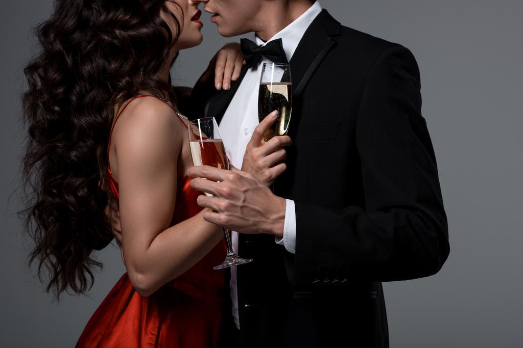przycięty widok para przytulanie i trzymając kieliszki szampana, izolowane na szarości - Zdjęcie, obraz
