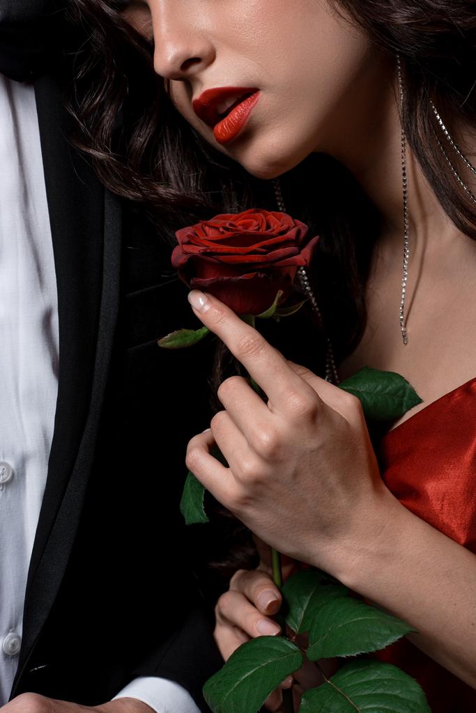 Ausgeschnittene Ansicht von Paar, das sich umarmt und rote Rose in der Hand hält  - Foto, Bild