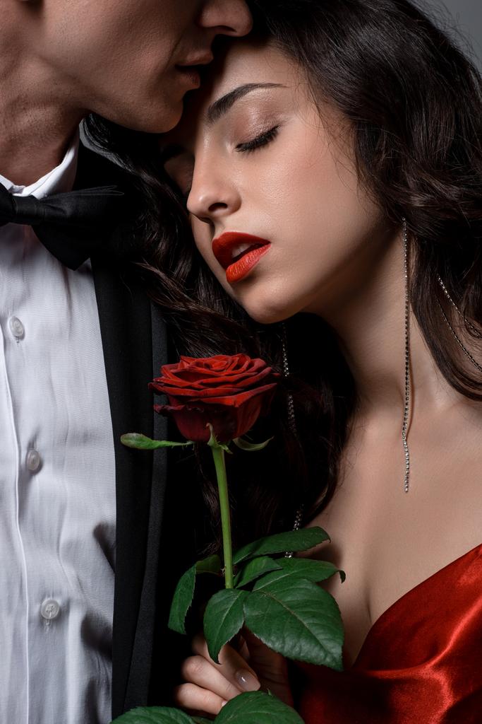 vista recortada de pareja romántica abrazando y sosteniendo flor de rosa roja
  - Foto, Imagen